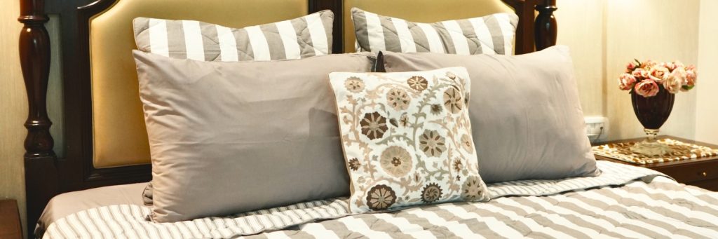 Elegant bedroom setup featuring cotton bedding with striped pillows, a patterned cushion