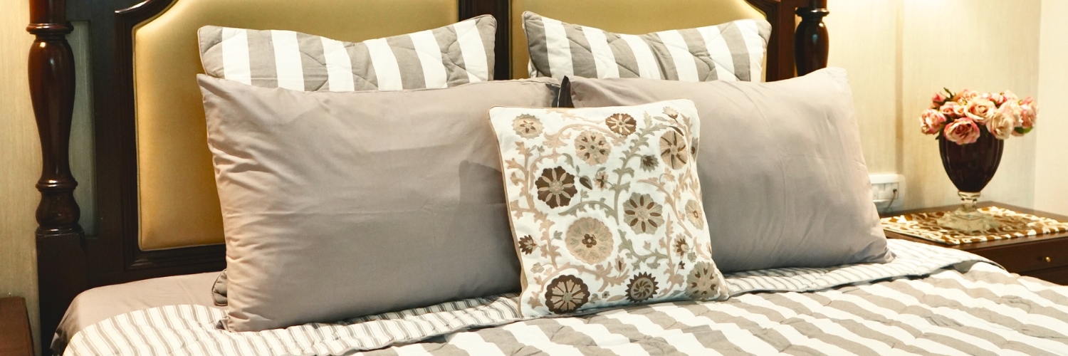 Elegant bedroom setup featuring cotton bedding with striped pillows, a patterned cushion