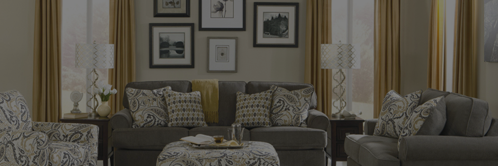 A living room featuring dark grey upholstered sofas, patterned cushions, and mustard-colored curtains