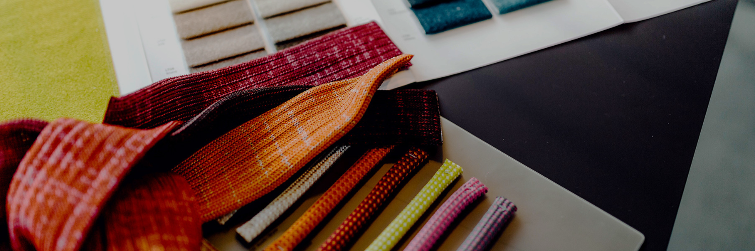 A vibrant textile samples in various colors and patterns, displayed on a dark surface alongside swatches of fabric.