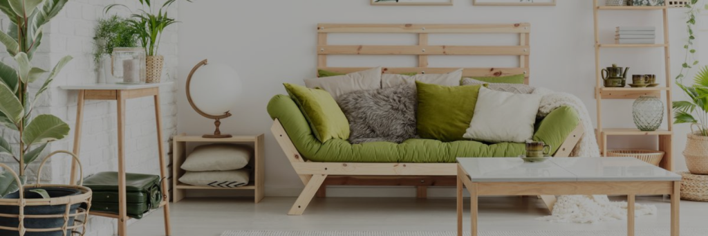 A cozy living room with a green cushioned sofa, wooden furniture, plants, and a minimalist decor.